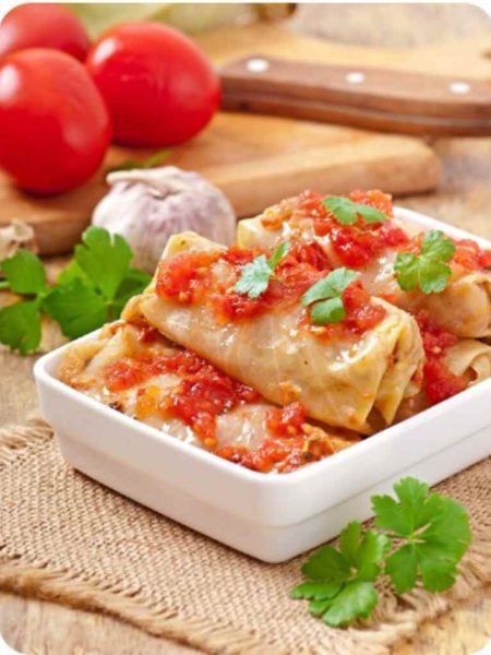 Sauté the onions in a cooking pan on medium heat for 2 minutes. Add the grated carrots and stir. Add the ground beef and pork and stir evenly. Season and pepper, sweet paprika and salt to taste. Add the egg to the sauce to bind all ingredients together. Add a half cup of water and a half cup of uncooked white rice. Stir and allow it to simmer for 2 minutes. Turn off the heat and set aside Trim the thick stem of the cabbage to make it easier to roll. Scoop one tablespoon of the ground meat sauce into one cabbage leaf and roll firmly. Set aside. Repeat until you roll all the ground meat. Brush the cooking pot with some oil and layer it with about 3 or more cabbage leaves. This prevents the cabbage rolls from sticking in the pot. Arrange the rolls on the cabbage leaves on the edges of the pot and add the smoked pork or beef ribs in the middle. Layer in the bay leaves and cover the contents of the pot with beef stock. Layer two more of the cabbage leaves on the rolls. Let it simmer for about 2.5hours on low heat. Check and add more broth or water occasionally. To make the roux, put the oil to heat and add the sweet paprika. Add 1 tablespoon of all-purpose flour and stir. Add a little water and mix until it reaches a smooth consistency. Add this mixture into the cabbage rolls pot, directly onto the meat in the middle. Allow the rolls to simmer for another 30 minutes. Serve and enjoy!