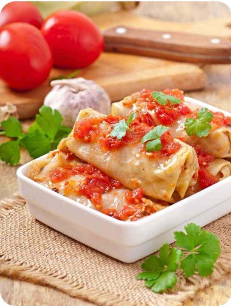 Sauté the onions in a cooking pan on medium heat for 2 minutes. Add the grated carrots and stir. Add the ground beef and pork and stir evenly. Season and pepper, sweet paprika and salt to taste. Add the egg to the sauce to bind all ingredients together. Add a half cup of water and a half cup of uncooked white rice. Stir and allow it to simmer for 2 minutes. Turn off the heat and set aside Trim the thick stem of the cabbage to make it easier to roll. Scoop one tablespoon of the ground meat sauce into one cabbage leaf and roll firmly. Set aside. Repeat until you roll all the ground meat. Brush the cooking pot with some oil and layer it with about 3 or more cabbage leaves. This prevents the cabbage rolls from sticking in the pot. Arrange the rolls on the cabbage leaves on the edges of the pot and add the smoked pork or beef ribs in the middle. Layer in the bay leaves and cover the contents of the pot with beef stock. Layer two more of the cabbage leaves on the rolls. Let it simmer for about 2.5hours on low heat. Check and add more broth or water occasionally. To make the roux, put the oil to heat and add the sweet paprika. Add 1 tablespoon of all-purpose flour and stir. Add a little water and mix until it reaches a smooth consistency. Add this mixture into the cabbage rolls pot, directly onto the meat in the middle. Allow the rolls to simmer for another 30 minutes. Serve and enjoy!